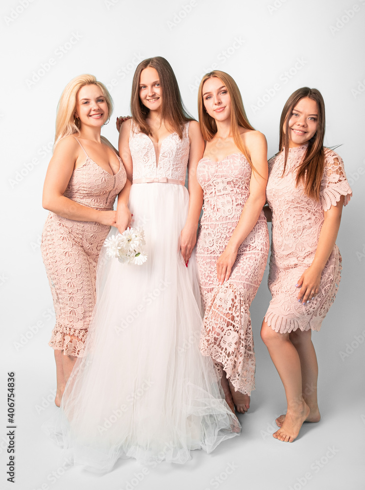 Happy wedding day. Event shooting. Beautiful smiling bride with bridesmaids in festive dresses looking at camera isolated on white.
