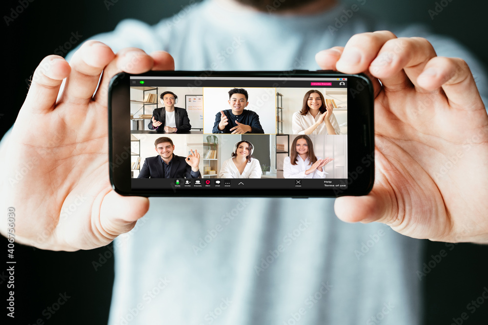 Video conference. Virtual meeting. Online communication. WFH telework. Man hands showing diverse multiracial team project discussion on mobile app phone screen on blur background.