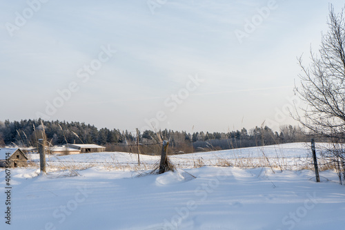 barbed wire fence with concrete poles in the snow, with airplane smoke in the background