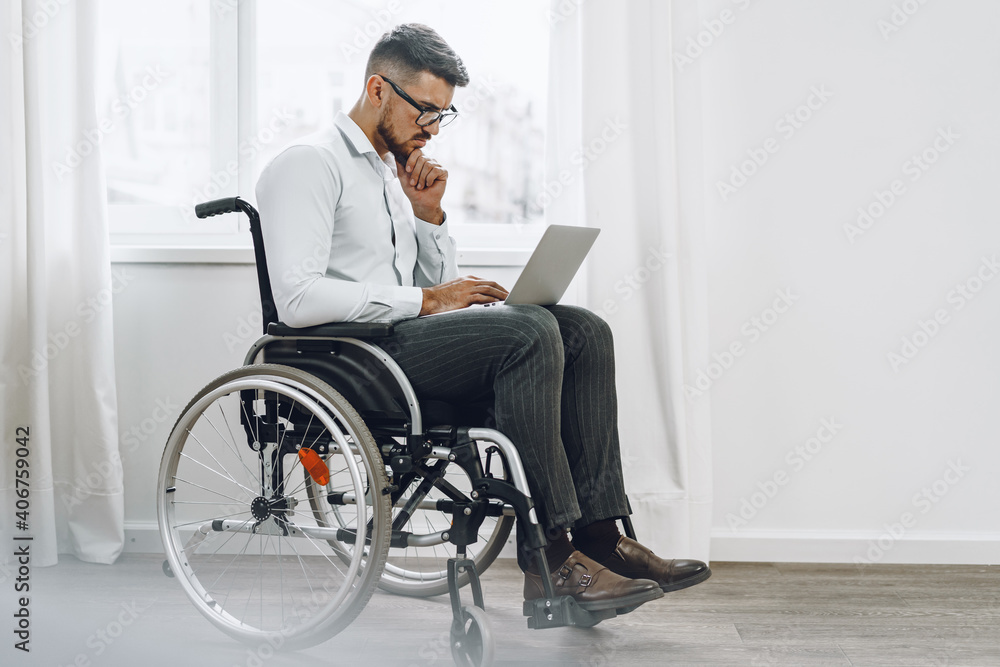 Businessman sitting in wheelchair and using laptop Businessman sitting in wheelchair and using laptop