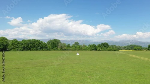 Newlyweds hug in the meadow. Sunny, bright day with blue sky and clouds. photo