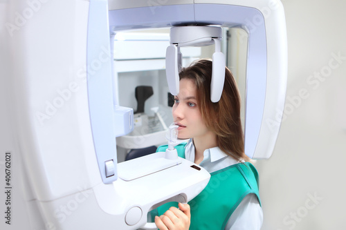 The girl in the X-ray room makes a panoramic picture of her teeth. Disease prevention and dental treatment. X-ray equipment. Panoramic image of teeth. Modern dentistry and medicine.