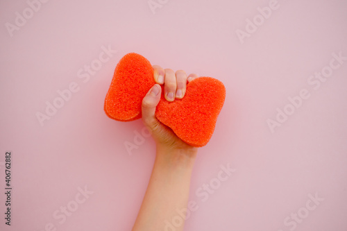mano sosteniendo una esponja de limpieza naranja sobre fondo de color  photo