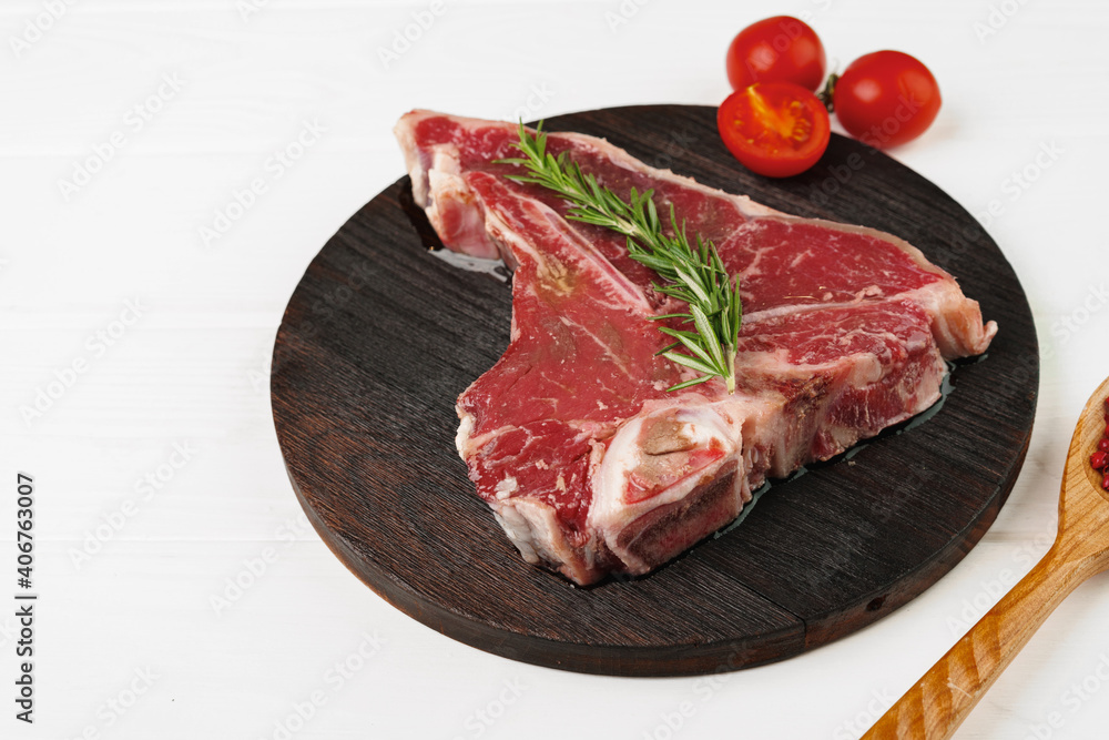 Raw t-bone steak on wooden cutting board on wooden table