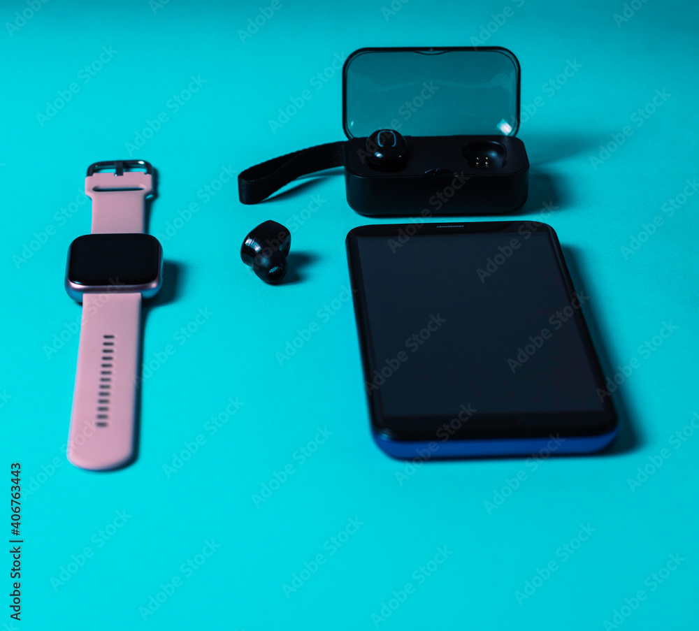 technological accessories smartphone 5g smartwach wireless headphones on neon blue background technological accessories smartphone 5g smartwach wireless headphones on neon blue background