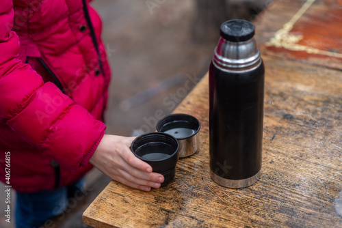 Thermos with hot tea on the table outdoors.