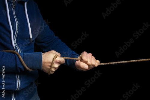 a Hands with a rope on a black background. A man pulls a rope wrestling. Drag the business to your side.