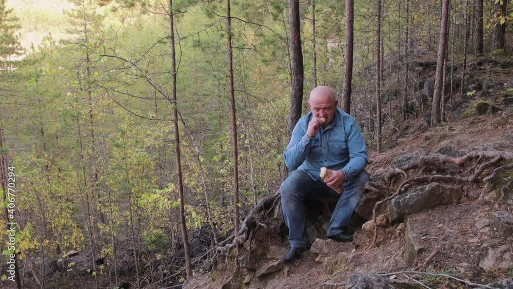 A man in jeans sits on the side of a quarry and eats a baguette. A wonderful view of the natural landscape. Tourist sightseeing. Picturesque expanses of the country. Summer travel at sunset. 4K. A man in jeans sits on the side of a quarry and eats a baguette. A wonderful view of the natural landscape. Tourist sightseeing. Picturesque expanses of the country. Summer travel at sunset. 4K.