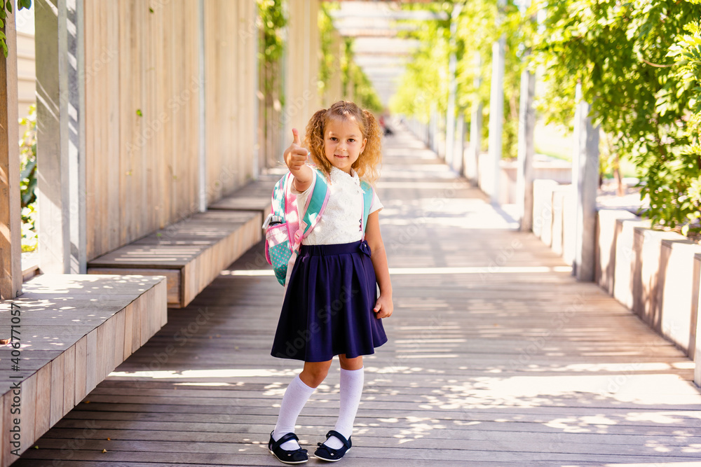 Happy little schoolgirl with school bag in school garden. Back to school outdoor