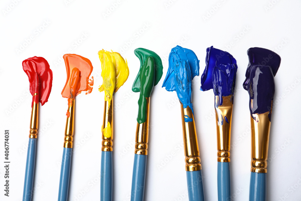 Set of brushes with different paints on white background, flat lay. Rainbow colors - obrazy, fototapety, plakaty 