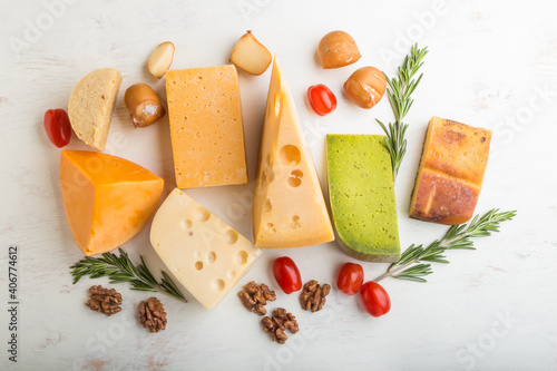 Set of different types of cheese with rosemary and tomatoes on a white wooden background . Top view.