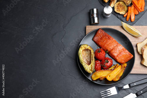 Obraz na płótnie Delicious cooked salmon and vegetables served on black table, flat lay