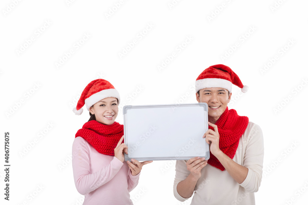 Portrait of young couple wearing Santa hats,holding whiteboard Portrait of young couple wearing Santa hats,holding whiteboard