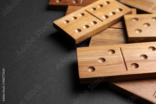 Wooden domino tiles on black background, closeup. Space for text