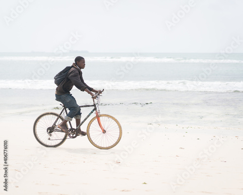 African young man riding bike on tropical beach