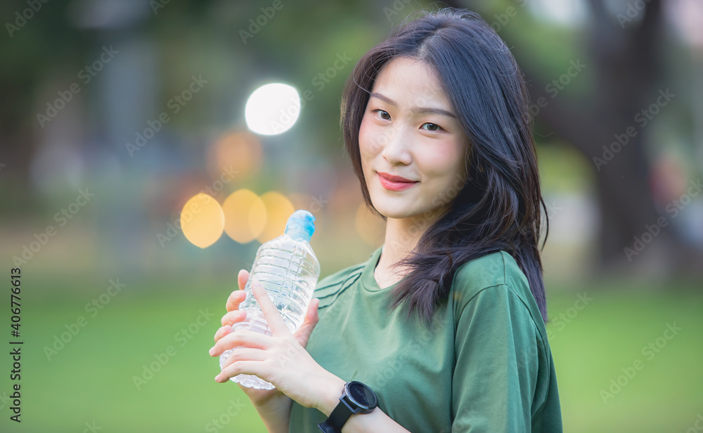 Young Asian woman drinking water after work out in the park Young Asian woman drinking water after work out in the park