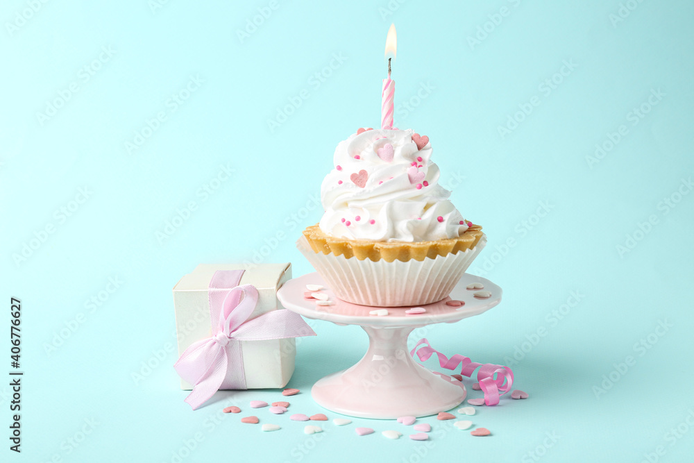 Delicious cupcake with candle and gift box on turquoise background Delicious cupcake with candle and gift box on turquoise background