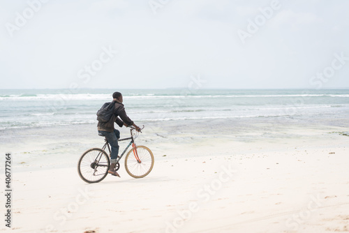 African young man riding bike on tropical beach