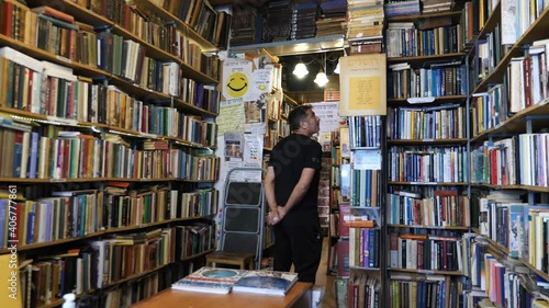 Customer in cozy secondhand bookshop looking at the books, bookstore interior