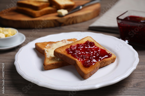 Fresh toast with jam and butter served on wooden table, closeup