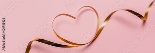 shape heart by gold ribbon on isolated pink background