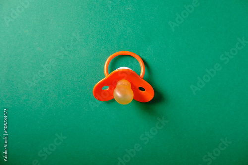 Baby pacifier on a green background, place for an inscription photo