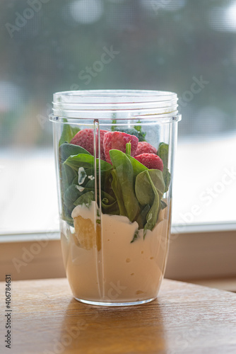 Healthy fruit, berry, spinach greens smoothie. Container of kale, banana, greek yogurt, protein and dairy ready to be blended. Protein meal replacement with antioxidants. 