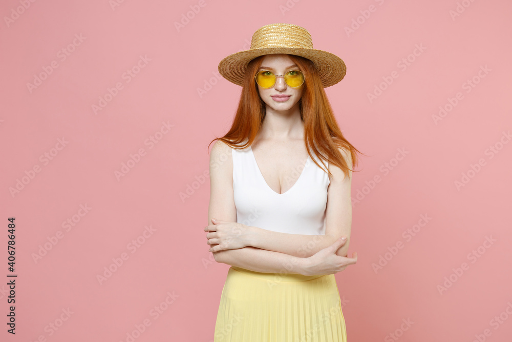 Young smiling cheerful caucasian nice redhead woman 20s ginger long hair wearing straw hat glasses summer clothes holding hands crossed folded isolated on pastel pink color background studio portrait. Young smiling cheerful caucasian nice redhead woman 20s ginger long hair wearing straw hat glasses summer clothes holding hands crossed folded isolated on pastel pink color background studio portrait.