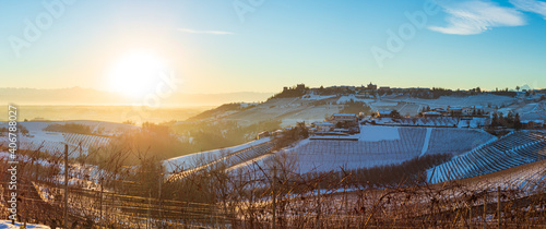 Italy Piedmont: Barolo wine yards unique landscape winter sunset, Novello medieval village castle on hill top, the Alps snow capped mountains background, italian historical heritage grape agriculture photo
