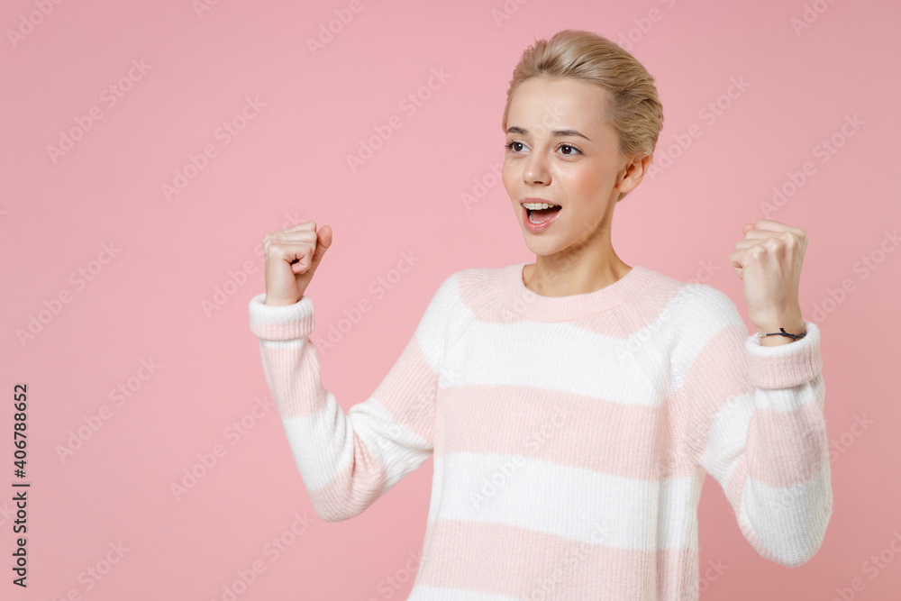 Young smiling fun cheerful blonde woman 20s short haircut dental braces in casual knitted sweater doing winner gesture clenching fists saying yes isolated on pastel pink background studio portrait. Young smiling fun cheerful blonde woman 20s short haircut dental braces in casual knitted sweater doing winner gesture clenching fists saying yes isolated on pastel pink background studio portrait.