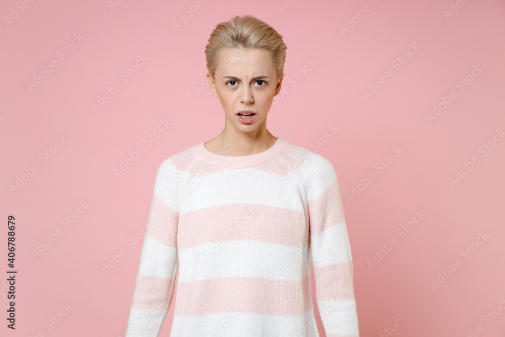 Young displeased shocked confused irritated caucasian blonde woman 20s with short haircut nude makeup wearing casual knitted sweater looking camera isolated on pastel pink background studio portrait.