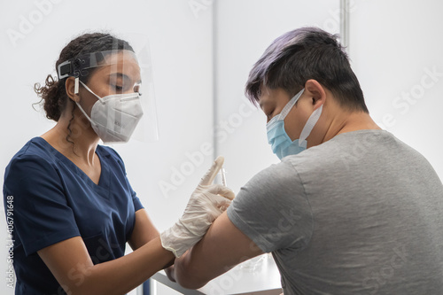 African American Black female Doctor prepares to administer vaccine to a Chinese patient in vaccination cabin. COVID-19 coronavirus vaccination
