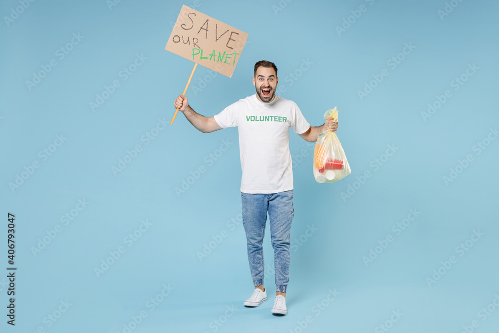 Full length shocked young man in white volunteer t-shirt jumping hold trash bag placard save planet isolated on blue background studio. Voluntary free assistance help trash sorting recycling concept. Full length shocked young man in white volunteer t-shirt jumping hold trash bag placard save planet isolated on blue background studio. Voluntary free assistance help trash sorting recycling concept.