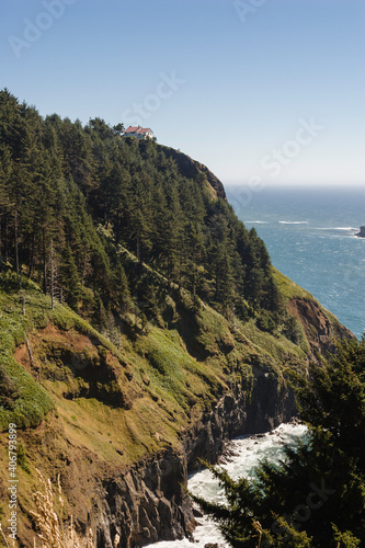 A lush green hill sits up over the ocean with cliffs plunging down towards the water below.