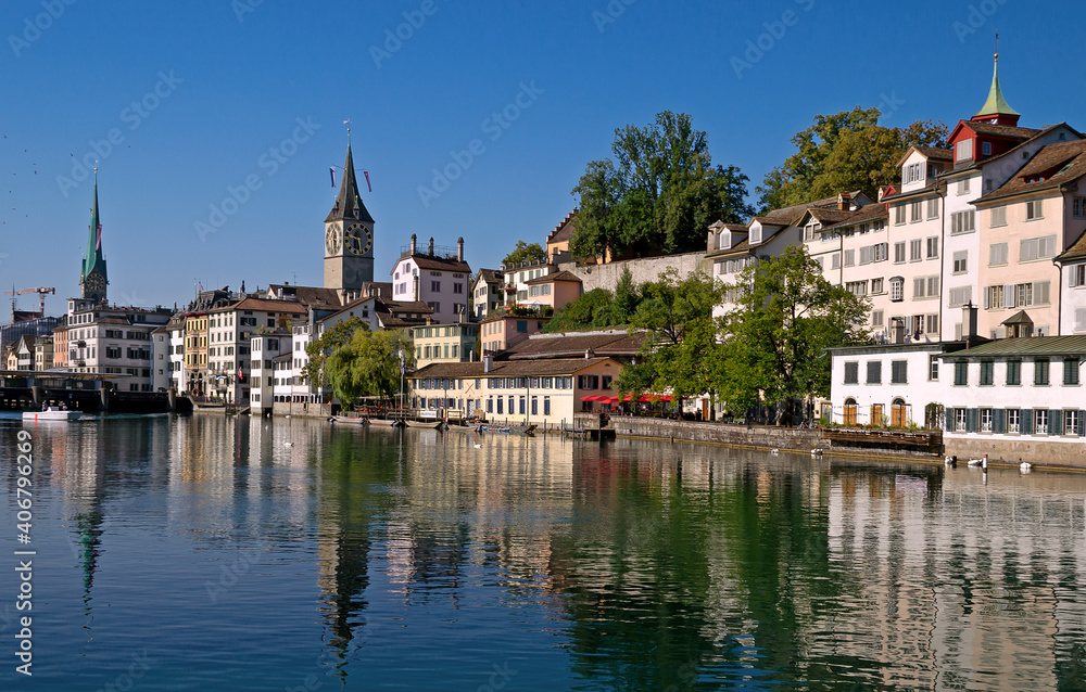Fototapeta premium Limnat River Cityview in Zurich, Switzerland showing the Church of St Peter spire in Summer