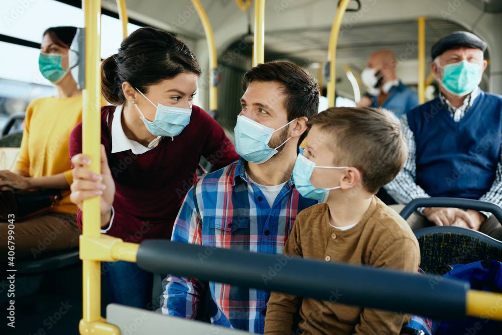 Happy family with face masks talking while commuting by public transport. Happy family with face masks talking while commuting by public transport.