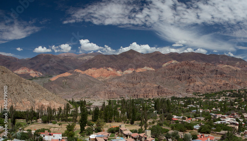 Tilcara village at the foot of the mountains. Panorama view of the colorful mountains and town buildings under a beautiful sky with clouds. 