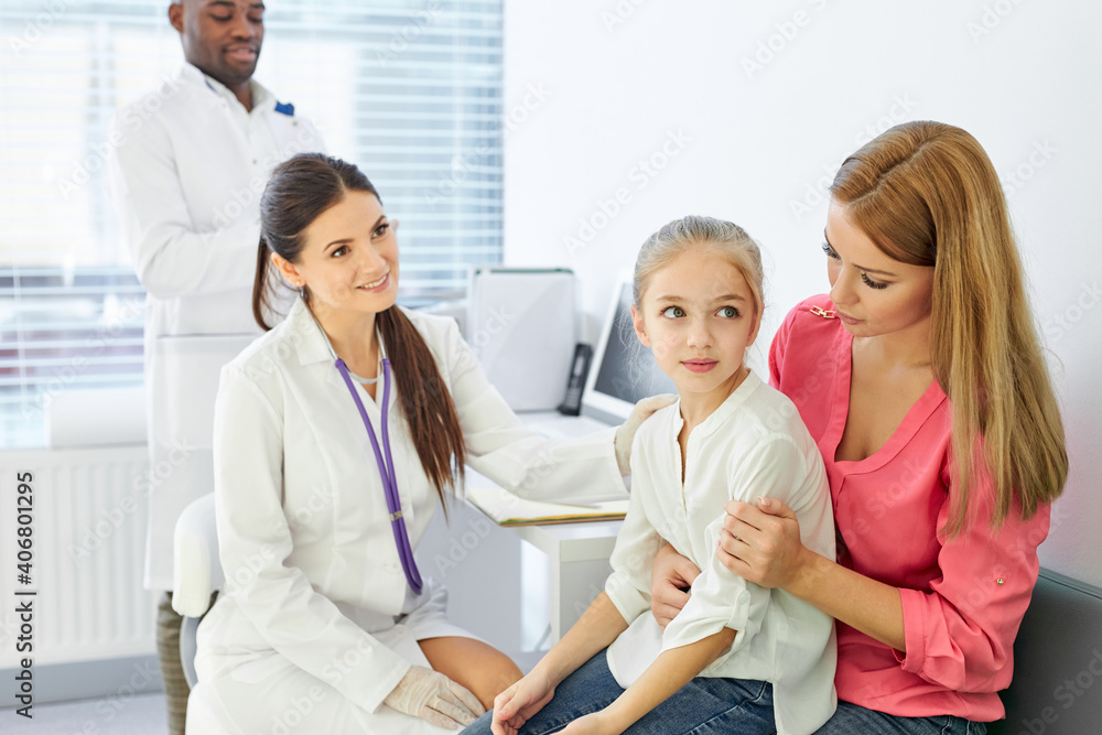 Fototapeta premium doctor talking to child and his mother during health checkup at the clinic, mom and girl get consultation by professional pediatrician or general practitioner during visit to the hospital