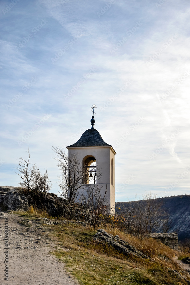 Monastery chapel with bell tower on background of picturesque mountain landscape. Religion, Christianity. Old Orhei, Moldova. Selective focus. Copy space. Vertical photo.