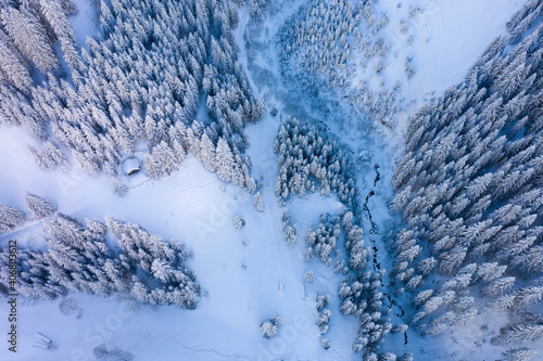View from above on lonely mountain hut in snowy forest clearing in winter