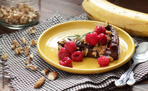 Chocolate vegan brownie cake with banana decorated with raspberry, walnut and rosemary, closeup, copy space, vegan eggfree desserts concept photo
