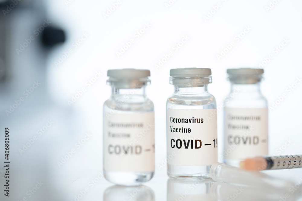 Coronavirus vials with a microscope on background. Coronavirus vials with a microscope on background.
