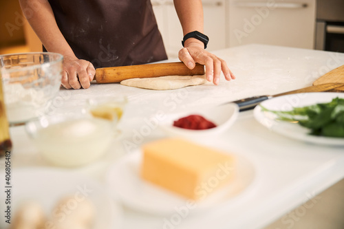 Unrecognized person using rolling pin in the kitchen