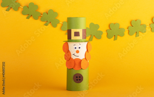 Leprechaun made of handmade paper with green four-leaf clover on the background