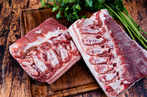 fresh pork belly on a used cutting board resting on an old wooden table photo