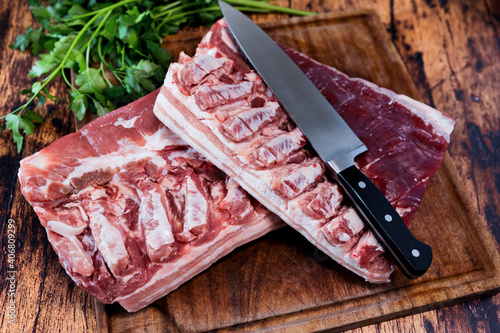 fresh pork belly on a used cutting board resting on an old wooden table photo