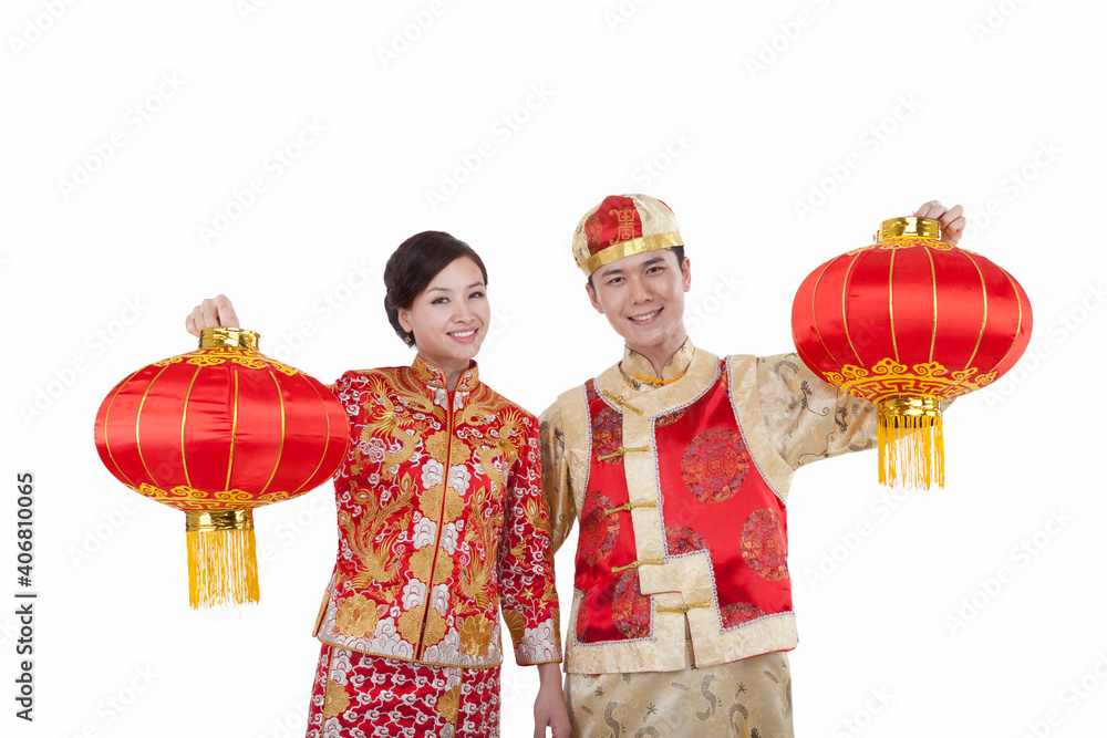 young couple in Tang suits paying New Year call holding red lanterns