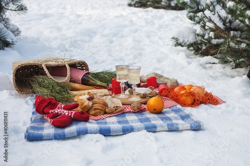 Romantic picnic setting in winter park, color blanket. Fresh food, cheese, oranges, croissants, wine and walnuts. Outdoor relaxing, fresh air eating.