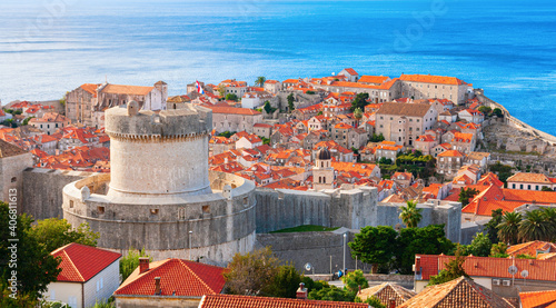 Houses with orange roofs of the Dubrovnik old town sourrounded by medieval city walls and the Minceta tower on a sunny morning. In the background the Adriatic Sea. Dubrovnik-Neretva, Croatia.