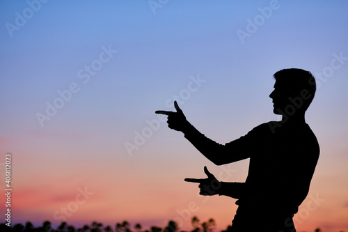 Men silhouette at sunset, human body over natural colorful sky background, hands up having fun